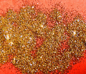gold glitter scattered on a red background, background of sequins closeup, selective focus