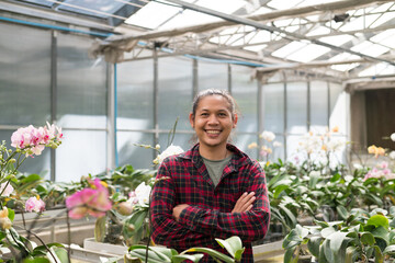 Obraz premium Portrait of young man Asian farmer smiling and arms crossed in Phalaenopsis orchid greenhouse