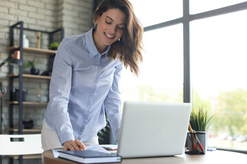 Young business woman standing in her home office reading notes.