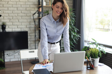 Young business woman standing in her home office reading notes.