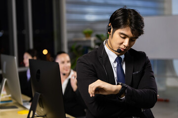 Businessman looking at the time on his wrist watch in call center office.