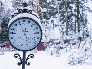 Street old style thermometer in the snow in the garden on the background of a snowy garden