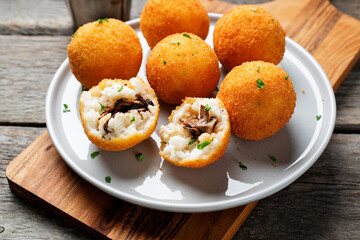 Homemade Fried Risotto Arancini stuffed with mushroom and parmesan cheese, served with tomato sauce.