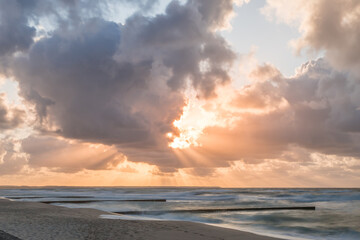 Naklejka na ściany i meble Golden sunset with dramatic cloudscape over the sea.