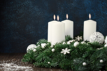 Christmas winter table setting with advent Xmas wreath, white candles, green branches and...