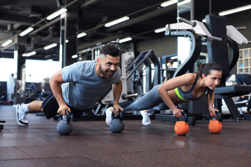 Fototapeta na wymiar Sporty man and woman doing push-up in a gym.