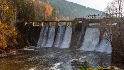Hydroelectric dam on a mountain river in an autumn forest