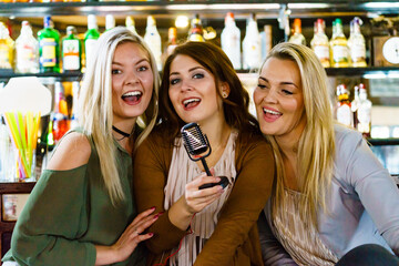 Women in bar singing karaoke