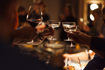 Glasses of wine in people's hands raised on toast.