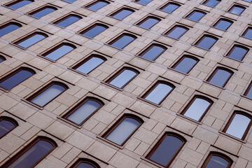 Several windows in a row on the facade of a modern building. Windows in a row on a marbled wall. Rows of windows on a high building. Toned image.