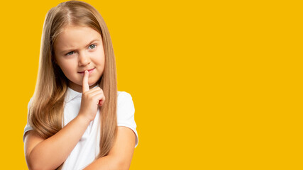 Curious child. Advertising background. Hard choice. Portrait of puzzled confused small girl thinking considering option isolated on orange copy space.