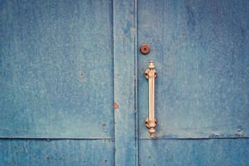 Wooden blue door with rusted handle. Old metal handle on blue wooden door. Toned image.
