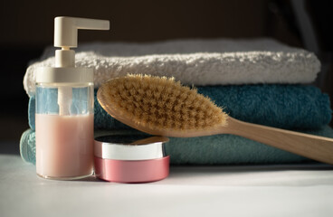Shower facilities and a stack of clean towels in the bathroom. Wooden brush for dry massage, liquid soap and body cream.
