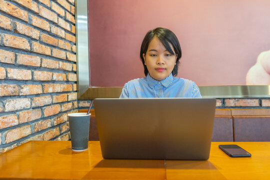 Asian Millennial Businesswoman Working On Laptop Next To Smartphone 