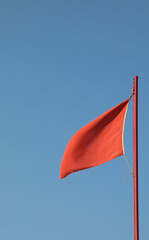 red flag waving to indicate danger with the background of blue s