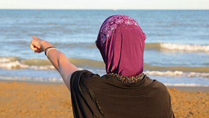 young girl with a veil to cover her hair and head while pointing