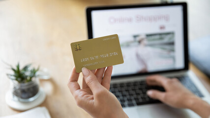 Crop close up of woman shopping online on laptop at home use credit card for payment. Female client...