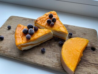 Pieces of pumpkin cheese pie on kitchen board