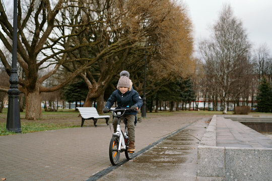 6 years old caucasian boy riding a bicycle in park on autumn day