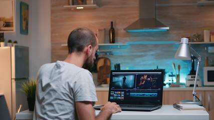Freelancer editing a video using post production software working from home overtime sitting in the...