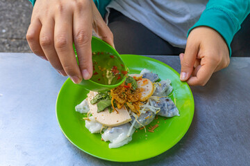 Woman eating Vietnam steamed rice rolls with chili fish sauce