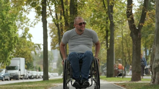Handicapped man in wheelchair walk at the park alley