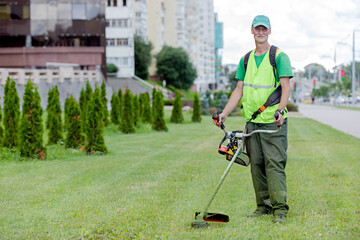 Municipal services senior worker gardener with lawn mover grass trimmer on city street background