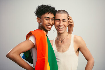 Cheerful gay couple with pride flag