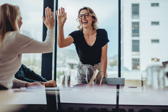 Business women high five in a board room meeting