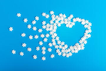 heart made of white snowflakes on a blue background. symbol of love and health. Copy space