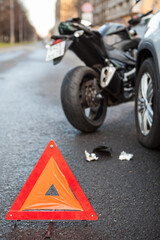 Fototapeta premium Emergency road triangle sign is on asphalt, road accident with car and motorcycle