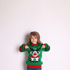 Cute little girl pointing at her green Christmas sweater against white background