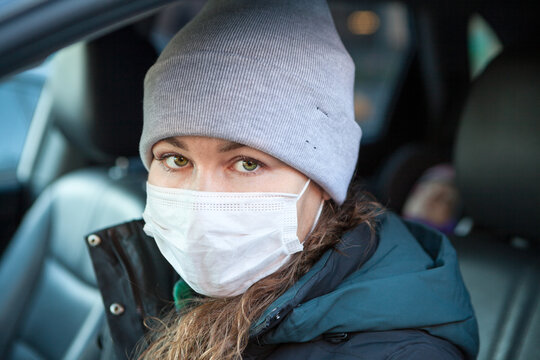 Portrait Of Woman Driver Wearing Facemask In A Car, Winter Season, Female Dressing Hat And Coat