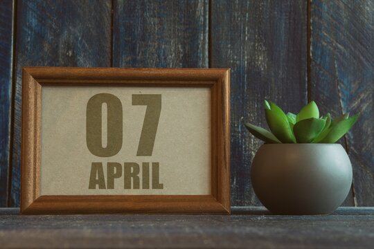 april 7th. Day 7 of month, date in frame next to succulent on wooden background spring month, day of the year concept