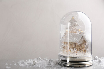 Beautiful snow globe on grey table against light background, space for text