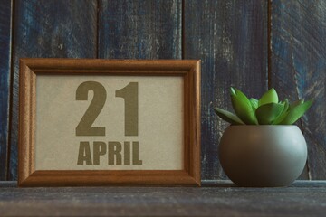 april 21st. Day 20 of month, date in frame next to succulent on wooden background spring month, day of the year concept