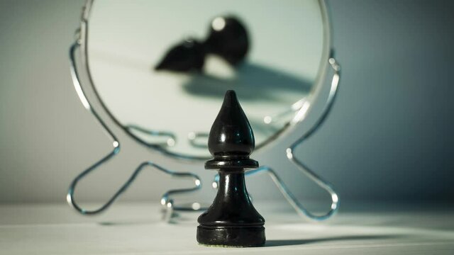 A chess piece is reflected in the mirror. Things and people are not what they seem. Reassessment of their abilities. Psychology, motivation. Power of thought. Never give up, always go for your goal.