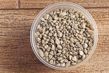 Top view of a plastic jar with decorative stones on a wooden surface