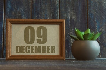 december 9th. Day 9 of month, date in frame next to succulent on wooden background winter month,...
