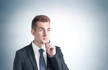 Thoughtful young businessman with pen, mock up
