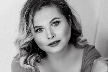 Black and white portrait of young  beautiful plus size woman indoor. Body positive. Femininity and modern lady concept. Attractive plus-size woman with curvy hair. Chic of natural beauty. Film grain