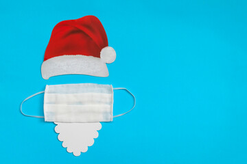 Santa Claus hat and beard with medical mask on light blue background. Christmas and New Year concept.