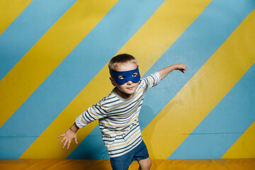 Funny cute boy in mask in entertainment center in trampoline room