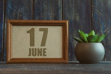 june 17th. Day 17 of month, date in frame next to succulent on wooden background summer month, day of the year concept