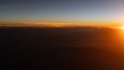 Fototapeta na wymiar Dramatic sunset scenic. View of sunset above clouds from airplane window.