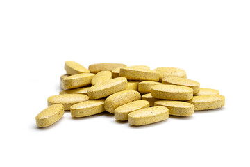 Close-up of a pile of yellow and brown colored pills or capsules on isolated white background. Selective Focus.