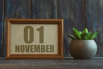 november 1st. Day 1 of month,  date in frame next to succulent on wooden background autumn month, day of the year concept