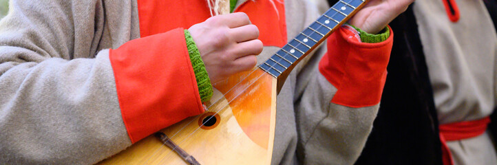 a man's hand plays the balalaika. male musician with a traditional Russian musical instrument in...