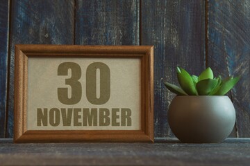 november 30th. Day 30 of month, date in frame next to succulent on wooden background autumn month, day of the year concept