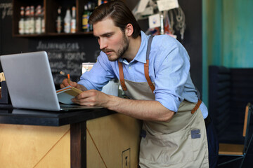 Restaurant manager working on laptop, counting profit.